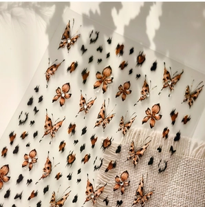 Detailed view of leopard print butterfly nail stickers with artistic plant shadow on white background