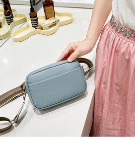 Close-up of blue-grey pebble leather camera bag with striped wide shoulder strap