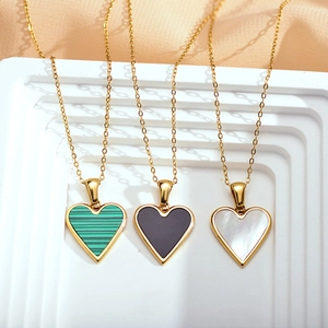 Close-up of heart-shaped pendants in malachite, onyx, and mother-of-pearl on gold chains