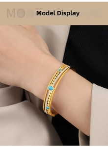 Close-up of vintage gold hollow cuff with blue turquoise and diamonds on model