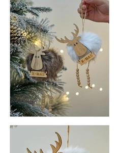 Close-up of plush reindeer ornaments with X-MAS wooden signs on a Christmas tree