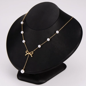 Elegant gold bow pendant necklace with pearls on a black mannequin display bust