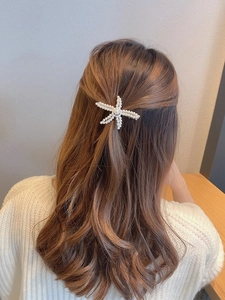 Detail of elegant pearl starfish hair clip on golden base worn on the back of the head