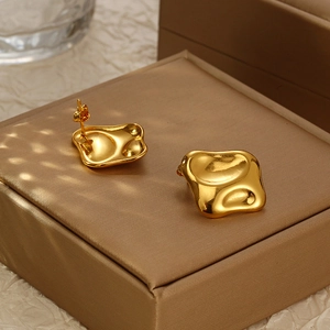 Polished 18k gold irregular hammered square stud earrings on a luxury jewelry box