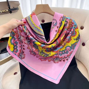 Detail of pink silk-like scarf featuring intricate colorful paisley patterns and soft texture