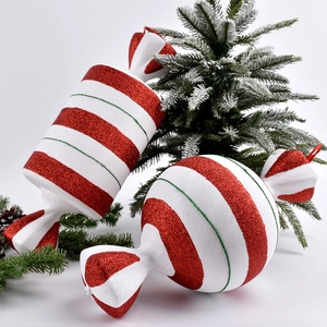 Red and white glitter candy ornaments with green details on pine branches background