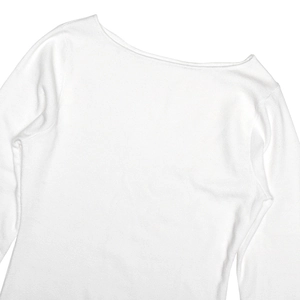 Detailed close-up of white long sleeve knit dress with ruffled edges and ribbed texture