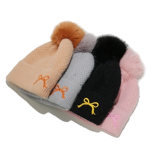Fleece-lined knit beanies with fluffy pom poms and bow embroidery in four colors
