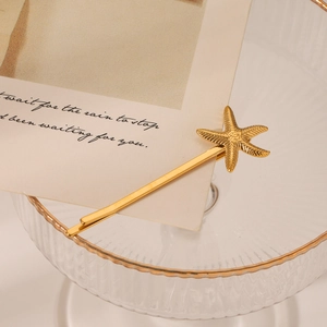 Pince à cheveux étoile de mer dorée sur carte vintage et support en verre