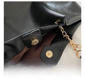 Gros plan de la boucle magnétique dorée sur un sac cabas en similicuir noir texturé