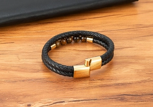 Detail of double-layer black leather bracelet with golden magnetic clasp and tiger eye stones