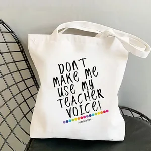Detail of white cotton tote bag with Don't Make Me Use My Teacher Voice print