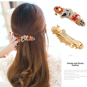 Detail of Halloween hair clip with pumpkin, skull and crystal charms on gold-tone alloy