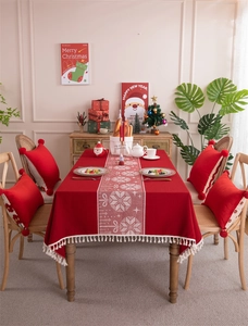 Macro detail of red Christmas jacquard tablecloth with white snowflake patterns and tassels