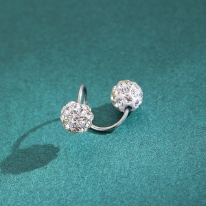 Macro shot of silver U-shaped ear cuff with sparkling crystal pavé balls on green texture