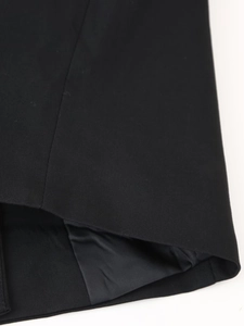 Dettaglio del vestito nero che mostra le cuciture dell'orlo e il tessuto a trama