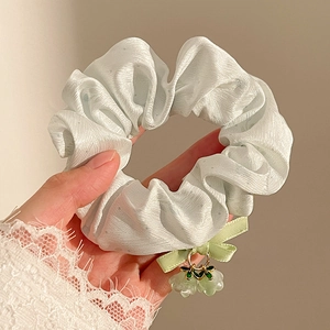 Detail of light green floral scrunchie with ribbon bow and flower charms for hair