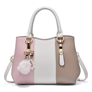 Fashionable color-block tote bag with pearl and pom-pom charms on white background