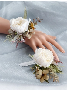 Detailed set of white artificial silk camellia wrist corsage and groom boutonniere