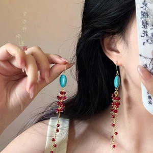 Close-up of vintage tassel earrings with turquoise stones and red berry-like bead clusters