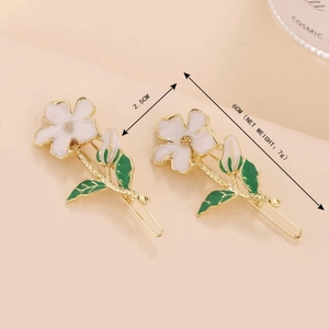 Floral hair clips with white enamel petals and green leaves on a golden frame