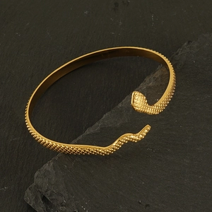 Vue détaillée du bracelet serpent doré avec texture d'écailles sur socle roche