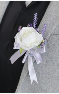 Close-up of artificial white rose boutonniere with lavender accents on a grey suit lapel