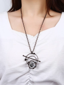 Detailopname van vintage bronzen ketting met wit kristal en hemelse maanbedeltjes