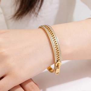 Detailed view of a gold zipper shaped bracelet with sparkling cubic zirconia inlay