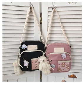 Détail de sacs bandoulière mignons noir et rose avec charms ours et sangles