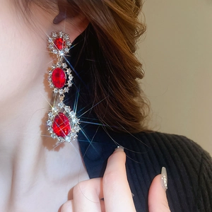 Gros plan de boucles d'oreilles à pompons avec pierres rouges et détails brillants