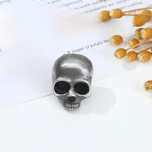 Detailed close-up of a vintage silver skull brooch with an antique matte gothic texture