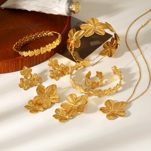 Détails d'une parure de bijoux dorés motif floral avec bracelet, bague et collier