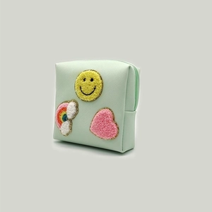 Detail of mint green PU leather pouch with chenille patches of rainbow, smile and heart