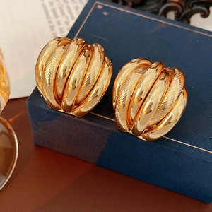 Detailed close-up of golden spiral texture earrings resting on a navy blue jewelry box