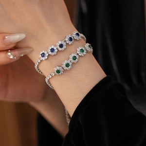 Détail de bracelets en argent avec fleurs en zircon bleu et vert sur un poignet de femme