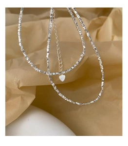 Detail of 925 silver irregular bead necklace with heart pendant on paper background