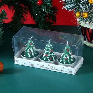 Detailed view of three green Christmas tree candles in a transparent gift box set