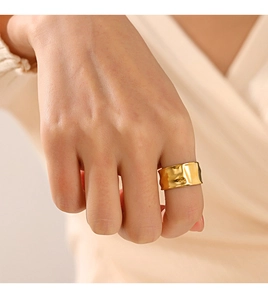 Detail of wide gold plated ring with irregular crumpled texture on female model's hand
