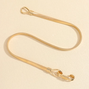 Macro shot of gold metal snake chain waist belt with elegant woven texture on beige backdrop
