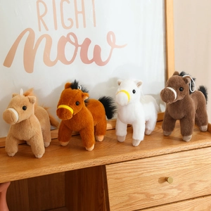 Set of four cute plush horse toys in different colors on a cozy wooden shelf