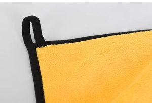 Macro shot of yellow microfiber pet towel fabric with black edges and hanging loop