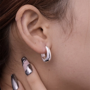 Close-up of polished silver U-shaped hoop earrings worn by a model for a modern look