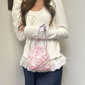 Quilted floral drawstring makeup bag with pink flower pattern and purple woven handle