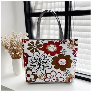 Detailed view of floral canvas tote bag with red-brown prints and grey fabric handles