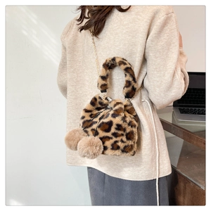 Detail of plush leopard print bucket bag featuring fuzzy pom-poms and metal chain strap