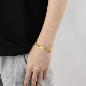 Gros plan d'un bracelet doré à plaque carrée avec un design à chaîne épaisse