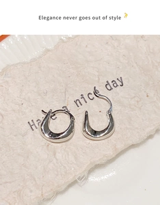 Macro detail of polished silver U-shaped earrings on textured paper with greeting