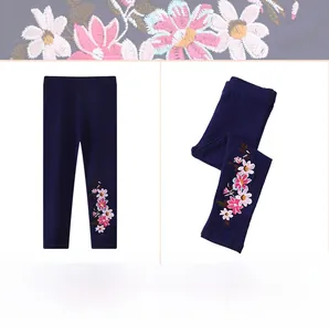 Gros plan de la broderie florale sur un legging en coton bleu marine pour fille