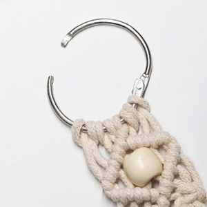 Close-up of beige woven cotton hat clip with square wooden bead and metal ring